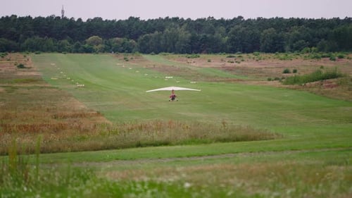 Motorized Glider Taking off From Lawn Runway on Summer Day