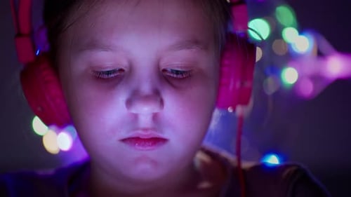 Child Wearing Headphones Looking at Screen at Night