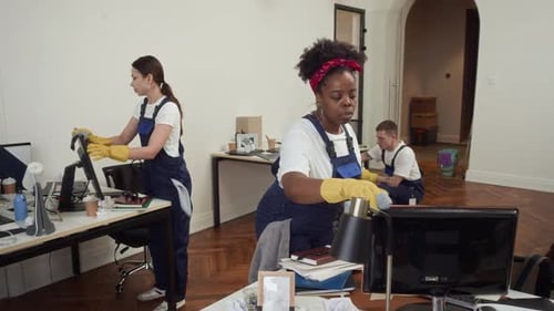 Team of Diverse Cleaners in Uniforms Wiping Office Equipment