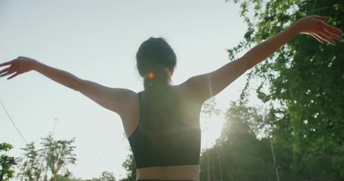 Woman Stretching Arms to Sky in Sunlight