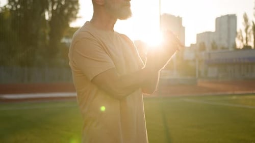 Senior Man Hand Stretching on Athletic Field