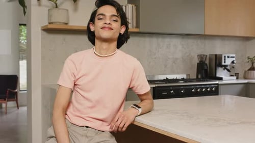 Homme adulte remarquant la caméra se transformant en sourire assis sur un comptoir en marbre montrant sa facilité
