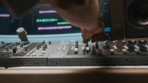 Hand Adjusting Dials on Mixing Console