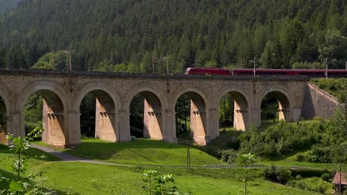 Slow pan over viaduct bridge at Semmering Railway with train running through it