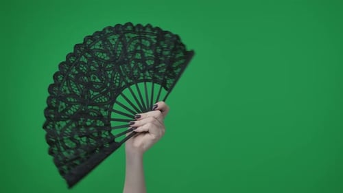 Na moldura em um fundo verde, uma chave cromada, mão feminina com manicure, segura um orifício preto