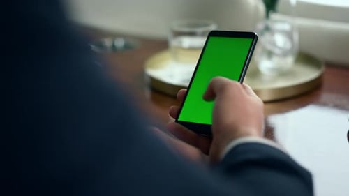 Man Hand Scrolling Green Smartphone Screen Closeup. Businessman Using Chroma Key Phone
