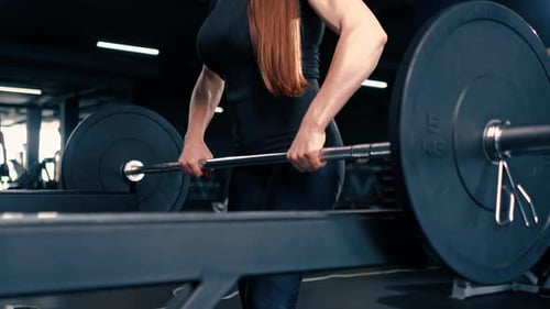 portrait of a concentrated fitness woman doing a heavy shoulder press exercise with a barbell in gym