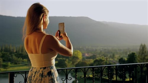 Woman Taking Picture with Smartphone on Balcony with Scenic Nature