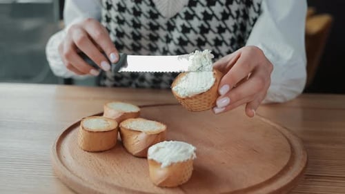 Woman Spreads Cream Cheese on Bread Slices