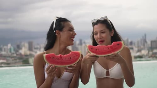 Female friends spend leisure activity at rooftop swimming pool.