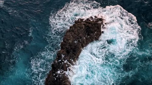 Top Down View of Ocean Waves Crashing Over Dark Rocks