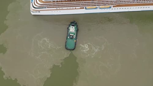 Tug boat assisting cruise ship arrival to port. Bottom sediment mixed by vessel propulsion. High alt