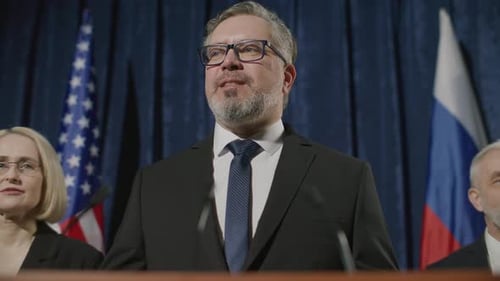 Man Giving Speech at Podium with Flags