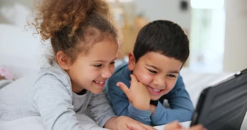 Two Children Watching Tablet on Bed Smiling