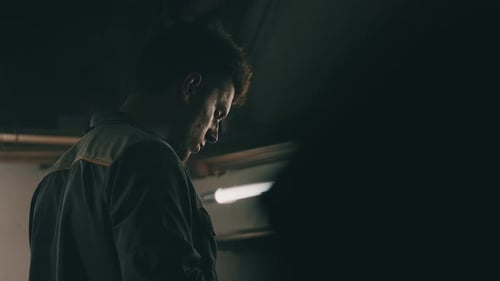 Side View of Mechanic Working in Garage at Night