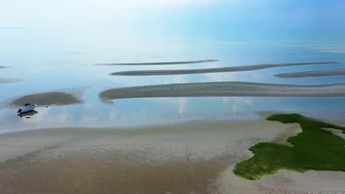 Drone Aerial View of Coastal Beach at Low Tide with Tidal Pools, Dunes, and Sky