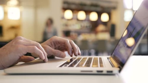 Hands typing on laptop computer in an office