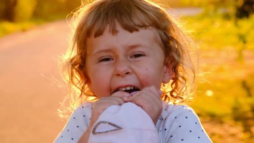 Laughing Girl Holding a Hat at Sunset