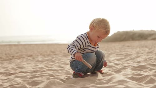 Blond Child Playing with Sand on Beach