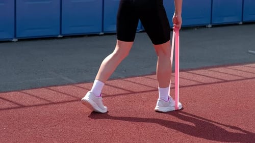 Woman Stretches Leg Muscles with Resistance Band