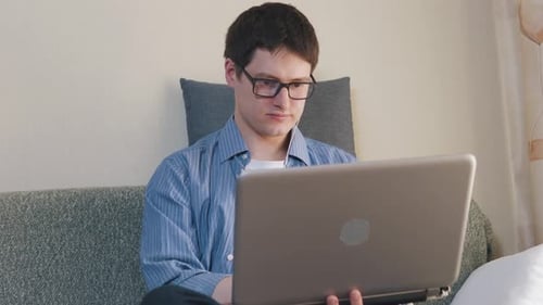 Man Uses Laptop on Couch at Home