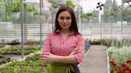 Woman Smiling in Greenhouse with Lush Plants