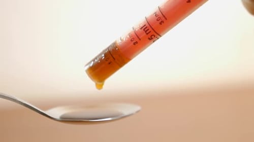 M54, À l'aide d'un distributeur, le médicament est versé dans une cuillère.