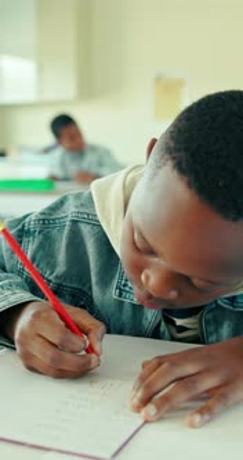 Boy, student and writing in classroom with notebook for math quiz, knowledge or curriculum activity