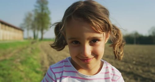 Authentic close up shot of cute little girl is smiling in camera outside her house on a sunny spri