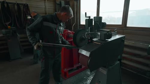 Man worker polishing the steel pipe at a factory workshop
