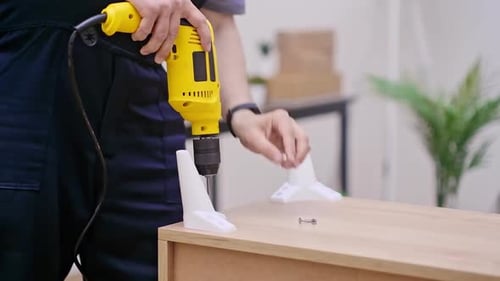 Drill Attaches Leg to Wooden Cabinet Close Up