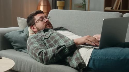 Man Lying on Couch Using Laptop at Home