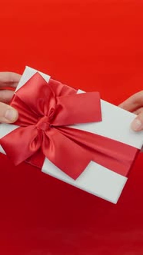 St. Valentine's Day gift with red ribbon against red background. Vertical video