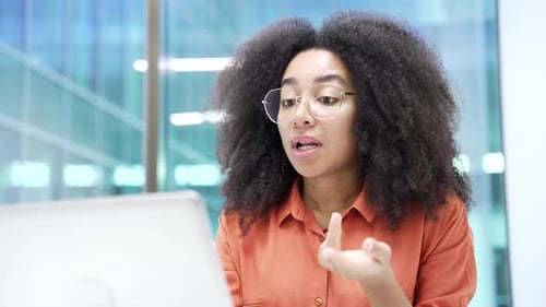 Confident african american businesswoman talking on video call using a laptop sitting in office.