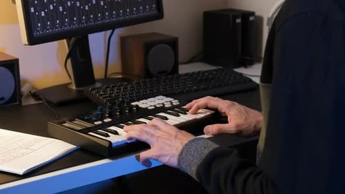 Person Playing Small Electronic Keyboard at Desk