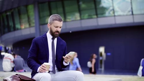 Bearded Man Drinks Coffee and Checks His Phone