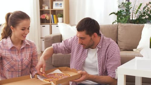 Couple Eating Pizza Together on Living Room Floor
