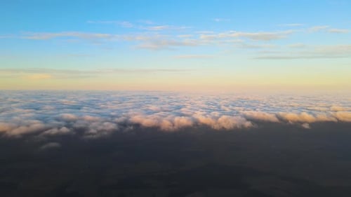 Blick aus großer Höhe auf den hellen, farbenfrohen Sonnenuntergangshimmel mit lebendiger, glatter, beleuchteter Wolkenschicht