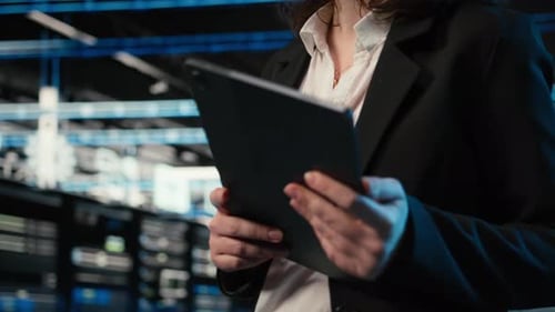 Closeup of Programmer Walking in Data Center Optimizing Server Load with Tablet