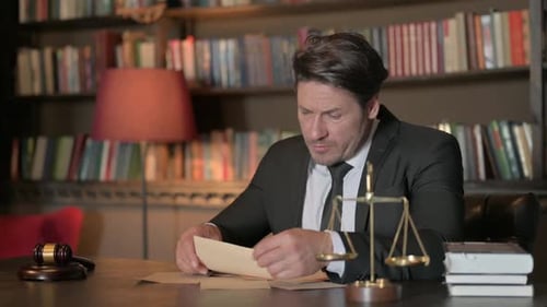 Pensive Male Lawyer Reading Documents in Office
