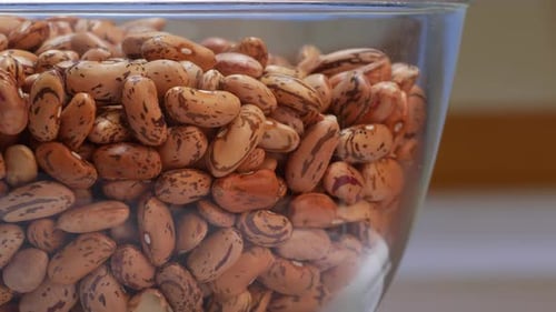 Primer plano de un tazón lleno de frijoles, algunos en un recipiente de vidrio y otros cubiertos con una tapa