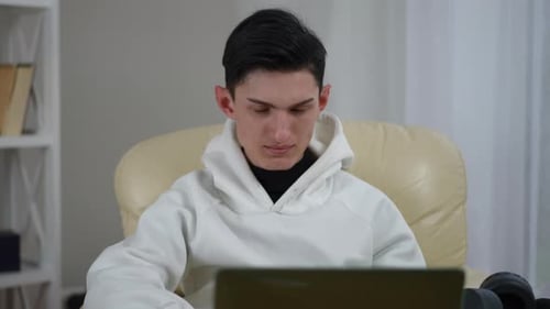 Young Adult Works at Laptop in Chair