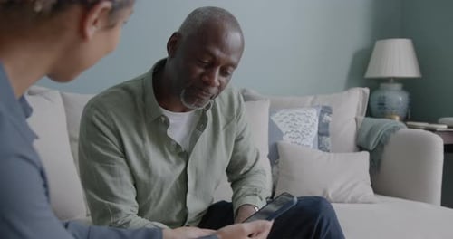 Woman and Man Looking at Smartphone on Couch Indoors