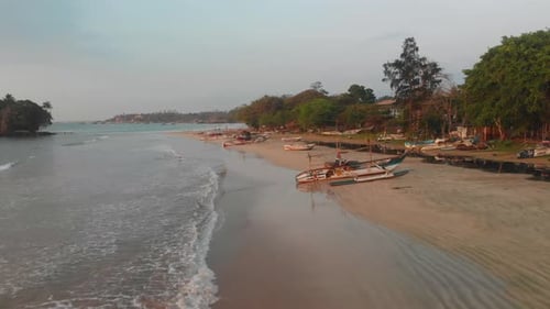 Aerial view of serene beach with boats at sunrise, Sri Lanka.