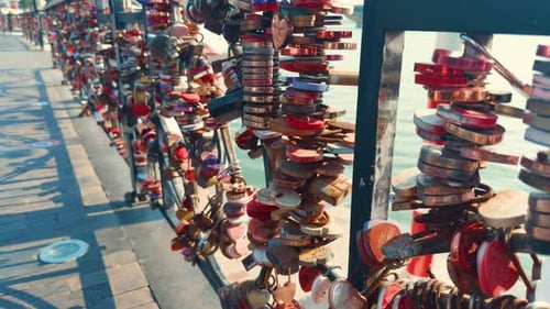 Love padlocks attached to a metal railing overlooking a river, showcasing a