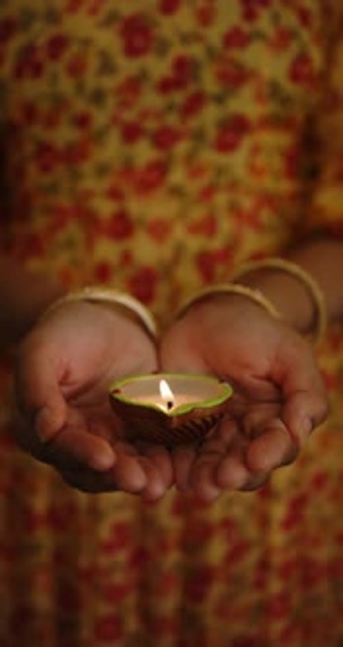 Woman Holds Lit Clay Candle in Her Hands