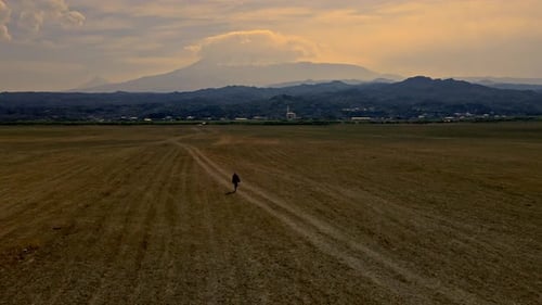 A man is walking in a field with a mountain in the background