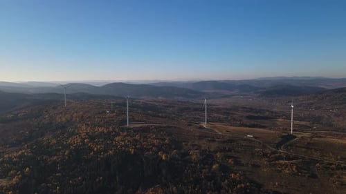 Aerial Panoramic View of a Group of Wind Turbines with Rotating Blades Working on a Hill with a