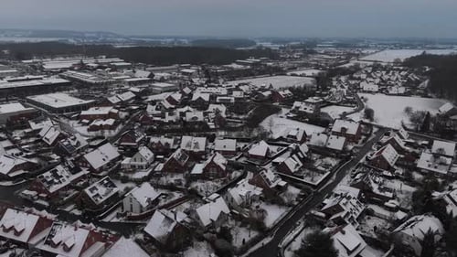 Snowy american residential area with industrial warehouses and rural farm fields in distance. Cold
