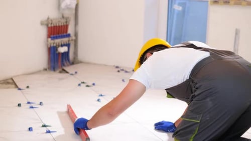 Man Leveling Tiles on Floor in a Home